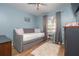 This bedroom with blue walls includes a daybed with a gray futon and a window with blinds at 5 Greenfern Cir, Ormond Beach, FL 32174