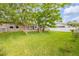 Large, fenced backyard with mature trees, green grass, patio and swing at 5478 Landis Ave, Port Orange, FL 32127