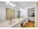 Bright bathroom with a double sink vanity, large mirror, curtained shower, and view to the main bedroom at 5478 Landis Ave, Port Orange, FL 32127