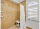 Tile shower with a window and a white curtain to the side, and a stool with shelves inside the shower at 5478 Landis Ave, Port Orange, FL 32127