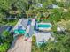 Stunning aerial view of turquoise home with lush landscaping, a private pool, and canal access at 61 E Bayshore Dr, Port Orange, FL 32127
