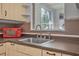 Classic kitchen sink with a window view, red microwave, and vintage cabinets at 61 E Bayshore Dr, Port Orange, FL 32127