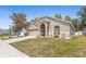 Side view of a tan-colored home with a two-car garage, arched entry, and manicured lawn at 700 Spring Cavern Ave, Orange City, FL 32763