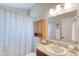 Cozy bathroom featuring a seashell shower curtain, granite vanity, and a wood cabinet over the toilet at 706 Fox Tail Ct, New Smyrna Beach, FL 32168