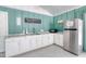A kitchenette area featuring white cabinetry, marble countertop, stainless fridge, and essential appliances at 706 Fox Tail Ct, New Smyrna Beach, FL 32168