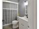 Well-lit bathroom features a toilet, vanity with a sink and a shower with gray and white curtain at 920 Trafalgar St, Deltona, FL 32725
