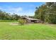 Aerial view showcasing a lush green field with an outbuilding and grapevines in the distance at 1056 Reynolds Rd, De Leon Springs, FL 32130