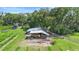 Aerial view of a barn with equipment, surrounded by trees and vineyard rows, highlighting the property's rural character at 1056 Reynolds Rd, De Leon Springs, FL 32130