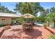 Outdoor deck with dining set, lounge and built-in grill area, surrounded by lush landscaping and mature trees at 1056 Reynolds Rd, De Leon Springs, FL 32130