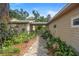 Charming home exterior with stone pathway, lush landscaping, and a welcoming entrance leading to the main house at 1056 Reynolds Rd, De Leon Springs, FL 32130