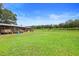 Wide shot of farmland with a tractor trailer, barn, vineyard, and green lawn at 1056 Reynolds Rd, De Leon Springs, FL 32130