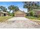 Two-car garage with an extended driveway, set against a backdrop of mature trees at 1056 Reynolds Rd, De Leon Springs, FL 32130