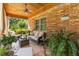 Relaxing covered porch with brick accents, comfortable seating, and lush greenery, perfect for outdoor living at 1056 Reynolds Rd, De Leon Springs, FL 32130