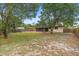 Expansive backyard featuring mature trees, a partial fence, and a covered patio for outdoor entertaining at 1204 Lawrence Ave, Deltona, FL 32725