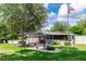 Spacious backyard features covered carport and patio with lush landscaping and flag at 136 W Gardenia Dr, Orange City, FL 32763