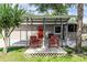 Charming home exterior with covered patio, cozy seating, and landscaped yard at 136 W Gardenia Dr, Orange City, FL 32763