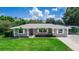 Charming single-story home featuring a well-manicured lawn, mature trees, and a covered parking area at 136 W Gardenia Dr, Orange City, FL 32763