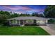 Charming single-story home featuring a well-manicured lawn, mature trees, and a covered parking area at 136 W Gardenia Dr, Orange City, FL 32763