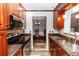 Galley kitchen boasts granite counters, stainless appliances, and cherry wood cabinets at 136 W Gardenia Dr, Orange City, FL 32763