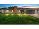 Exterior view of a one-story home accented by an attached garage, brick chimney, and well-lit lawn at dusk at 1483 Meadowlark Dr, Deltona, FL 32725