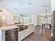 This open-concept kitchen features stainless appliances, a farmhouse sink, and flows into the dining and living areas at 1520 Stone Trl, Enterprise, FL 32725