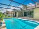 Sparkling swimming pool enclosed in a screened lanai featuring a deck and covered patio with columns at 1520 Stone Trl, Enterprise, FL 32725