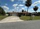 Charming single-story home featuring a long driveway, a two-car garage, a well-maintained lawn, and tropical palm trees at 15555 Sw 46Th Cir, Ocala, FL 34473