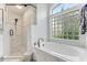Bathroom featuring marble tiled shower and separate tub with natural light from block window at 1910 Creekwater Blvd, Port Orange, FL 32128