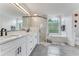 Bright bathroom with double vanity, marble countertops, glass enclosed shower, and separate tub with natural light from block window at 1910 Creekwater Blvd, Port Orange, FL 32128