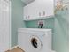 Well-lit laundry room featuring a modern washer and dryer with overhead storage cabinets at 1910 Creekwater Blvd, Port Orange, FL 32128