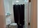 Compact bathroom featuring a toilet, sink, and dark shower curtain for privacy at 20422 Canvas Back Rd, Altoona, FL 32702