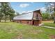 Exterior of a barn with wood siding, brick facade, metal roof, and a second-story balcony at 2221 Oak Hill Dr, Deland, FL 32720