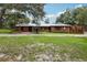 Charming one-story brick home featuring a metal roof, manicured lawn and mature trees at 2221 Oak Hill Dr, Deland, FL 32720