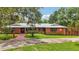 Charming single-story brick home with a metal roof, manicured lawn, and a welcoming entrance at 2221 Oak Hill Dr, Deland, FL 32720