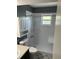 Bright bathroom with a white tiled shower, grab bar, window and vanity sink at 233 Elmwood Ave # 290, Deland, FL 32724