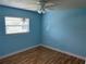This bedroom has light-blue walls, wood floors, a window, and a ceiling fan at 233 Elmwood Ave # 290, Deland, FL 32724