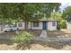 Inviting home featuring white siding, black trim, a blue door, and mature shade trees at 2434 Barbarossa Ave, Deltona, FL 32738