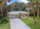 A well-maintained home boasts a long driveway, a spacious garage, and a beautifully landscaped yard creating a welcoming curb appeal at 2509 Kumquat Dr, Edgewater, FL 32141