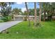 A charming home featuring a lush green lawn, mature trees, and a lengthy driveway leading to an attached garage at 2509 Kumquat Dr, Edgewater, FL 32141