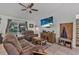 Cozy living room featuring plush reclining sofas, ceiling fan, mounted tv, and sliding glass door to the backyard at 2509 Kumquat Dr, Edgewater, FL 32141