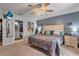 Well-lit main bedroom with a ceiling fan, guitars mounted on the wall, ensuite bathroom, and closet space at 2509 Kumquat Dr, Edgewater, FL 32141