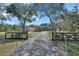 Gated home entrance with a long driveway, mature trees and a well-maintained fence at 2699 Audubon Ave, Deland, FL 32720