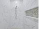 Luxurious shower with marble tile, rainfall showerhead, and decorative mosaic tile inset at 2894 Hardy Ave, New Smyrna Beach, FL 32168
