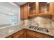 Kitchen sink features granite countertops, wood cabinetry with glass doors, and a tile backsplash at 2987 S Atlantic Ave # 903, Daytona Beach, FL 32118
