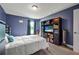 Cozy bedroom with blue walls, white comforter, and a black bookshelf featuring storage and a television at 37 Naranja Rd, Debary, FL 32713