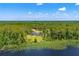 Stunning aerial view of a lakefront property surrounded by lush forest and water lilies, offering privacy at 5366 N Lake Farms Rd, De Leon Springs, FL 32130