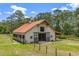 Beautiful barn with a metal roof, stall doors, and fencing, set in a grassy field at 5366 N Lake Farms Rd, De Leon Springs, FL 32130