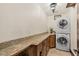 Functional laundry room with granite countertops, wood cabinets and stacked washer and dryer at 5366 N Lake Farms Rd, De Leon Springs, FL 32130