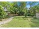 Lush backyard with green grass, mature trees, and a charming path leading to a quaint picket fence at 5635 Burts Park Rd, De Leon Springs, FL 32130