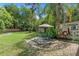 Lawn and seating area with an umbrella, adjacent to the cottage and surrounded by a privacy fence at 5635 Burts Park Rd, De Leon Springs, FL 32130